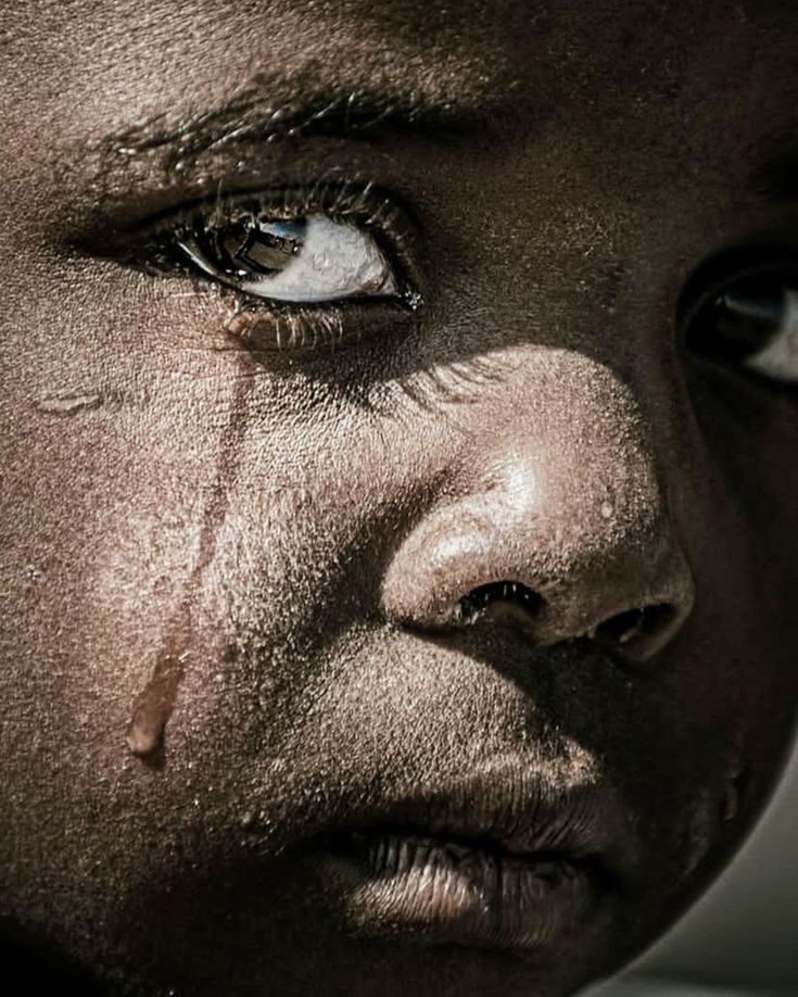 A close-up of a young Ghanaian child's face with a tear running down the cheek
